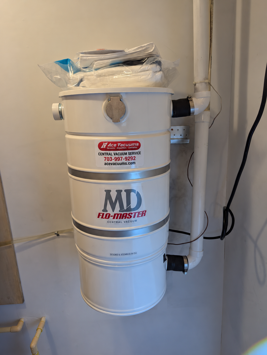 MD Flo-Master central vacuum power unit with white PVC piping and an AceVacuums service sticker at AceVacuums