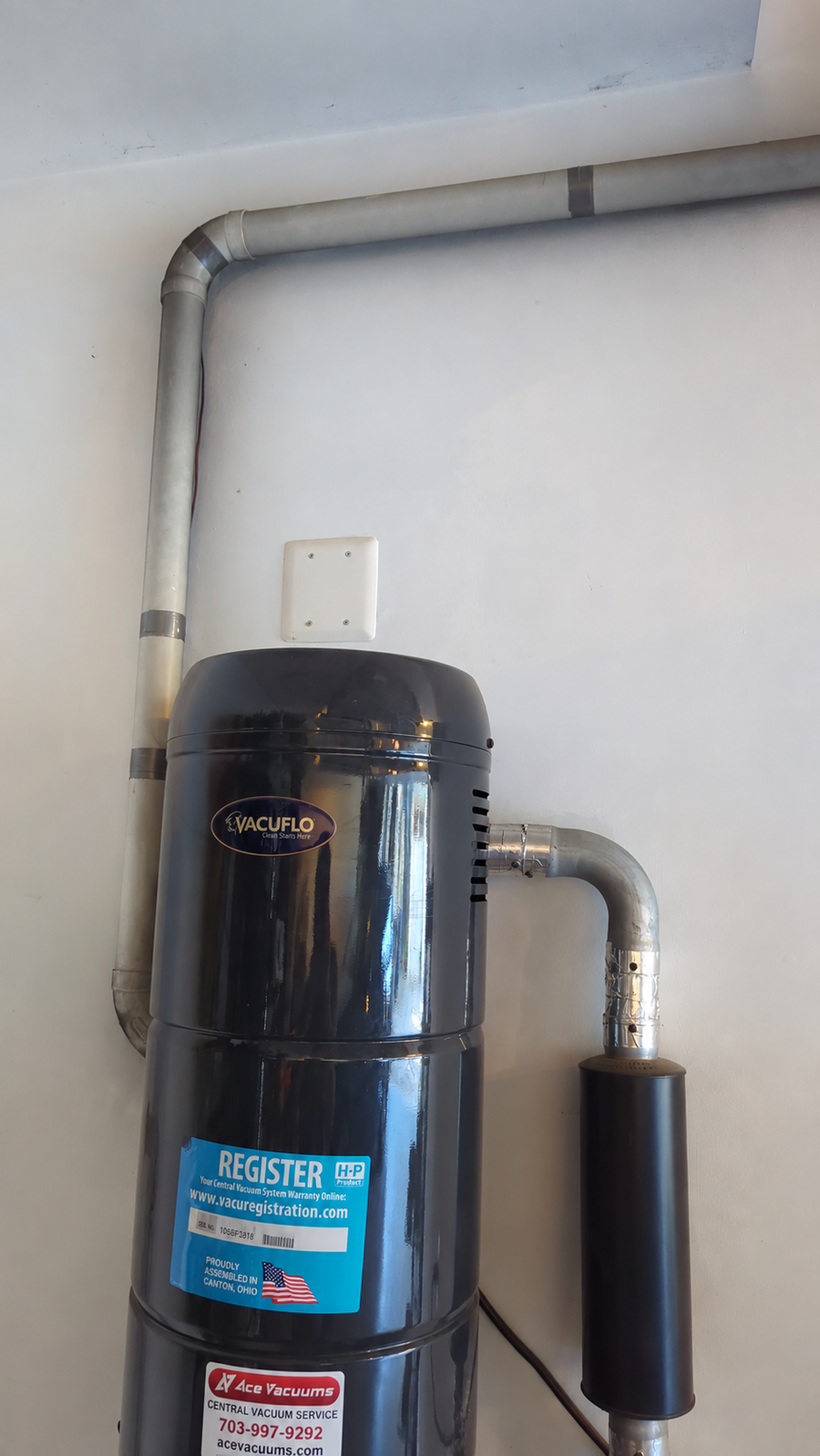 VACUFLO central vacuum system with wall-mounted piping, exhaust muffler and AceVacuums service label at AceVacuums