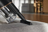 Miele HX-UN wide upholstery nozzle cleaning a fabric sofa