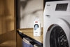 Miele Liquid Detergent UltraSoft Fabric Softener 11987230, beside a washing machine