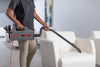 Oreck XL Pro 5 Super Compact Canister Bagged Vacuum Cleaner – Model #BB900-DGR – shoulder-carried vacuum cleaning a chair